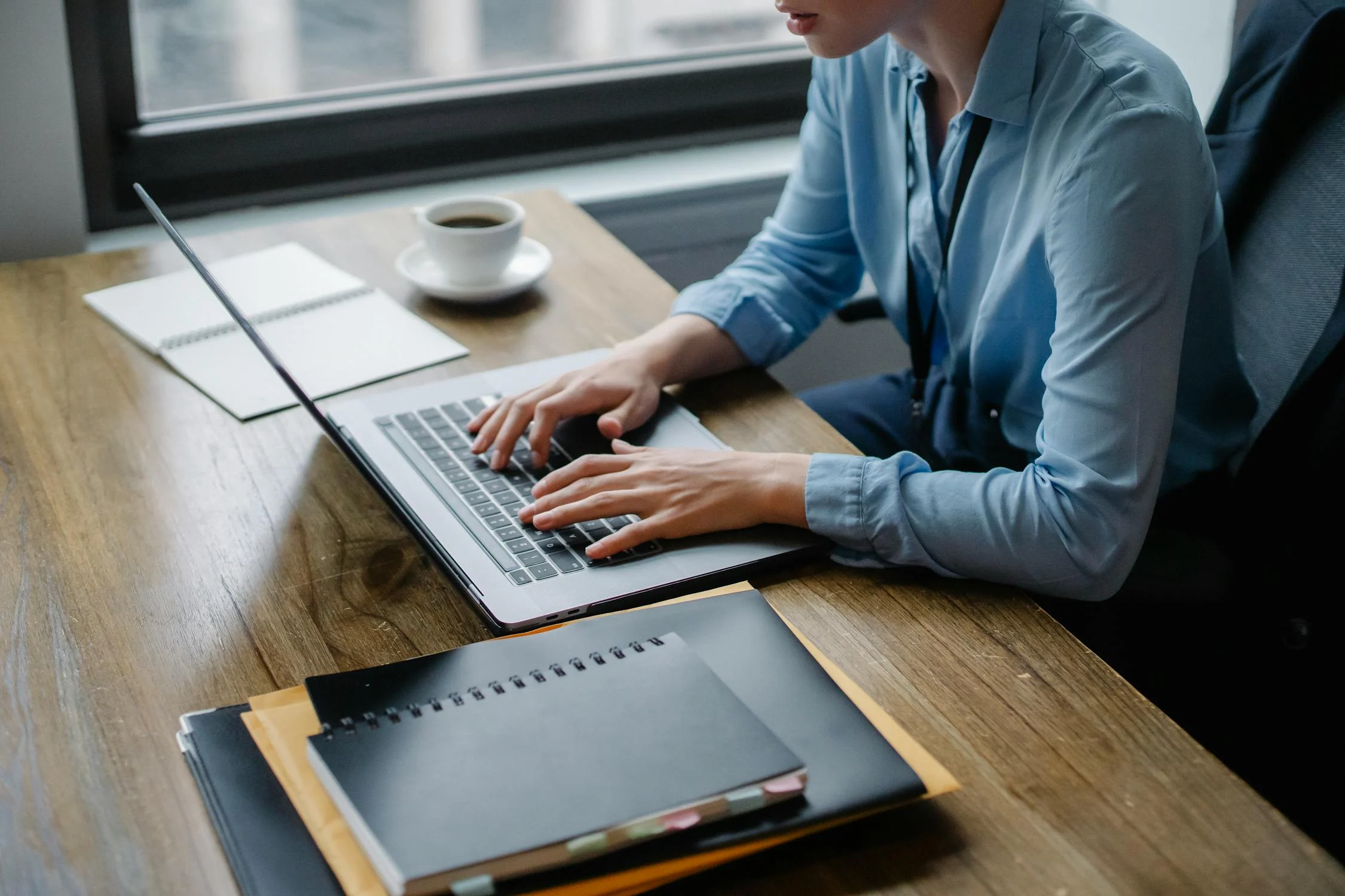 an employee wearing blue long-sleeve shirt typing on his laptop in the office