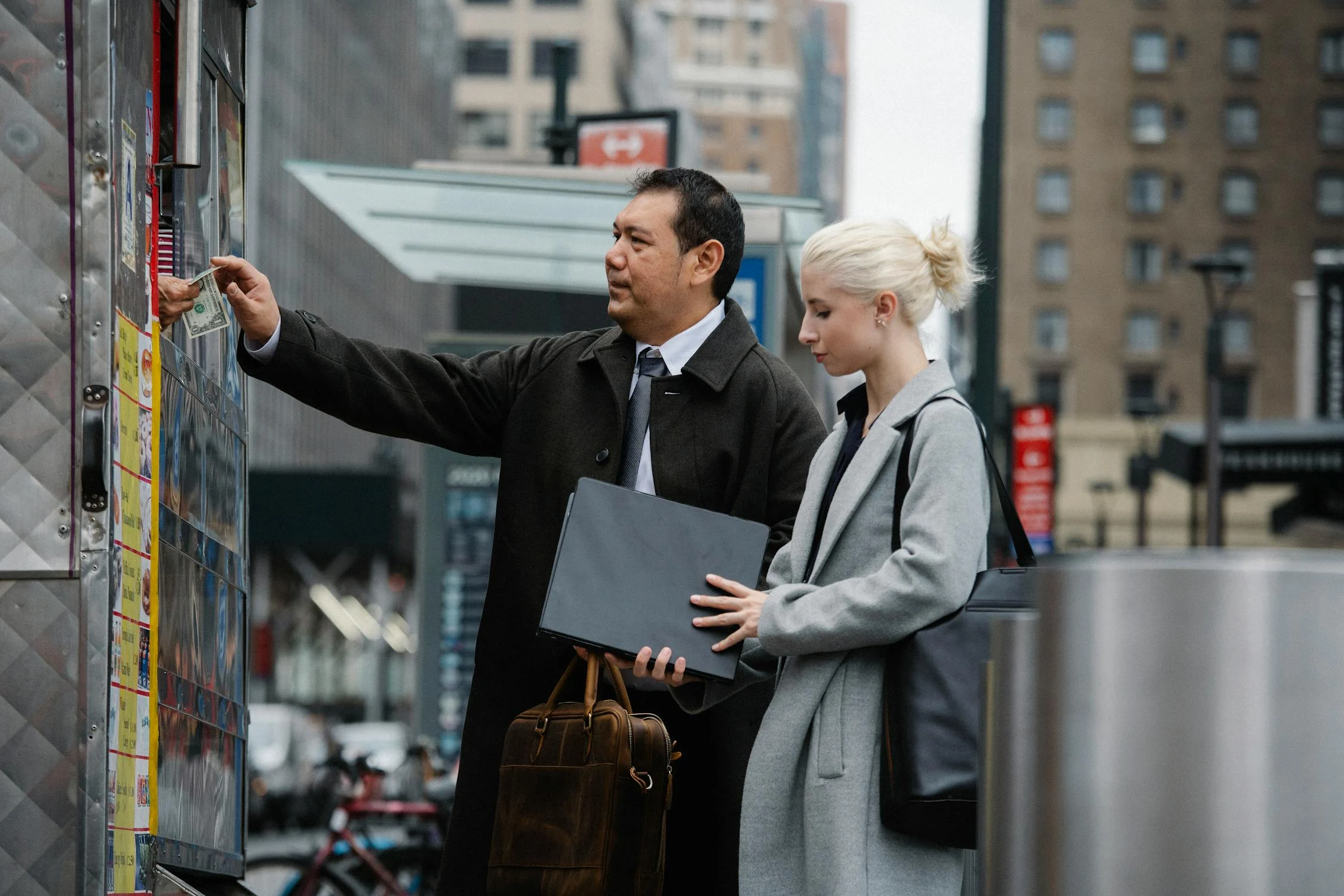 two colleagues having business trip to abroad and ordering street food while carrying their bags